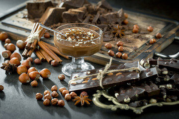 Pieces of dark chocolate and cocoa beans in composition on old background