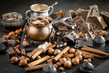 Pieces of dark chocolate and cocoa beans in composition on old background