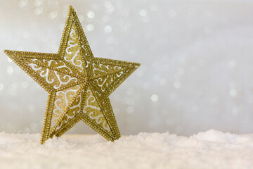 Fototapeta na wymiar Golden christmas star on snow with sparkle bokeh background with copy space