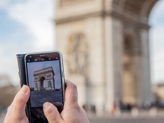 A tourist takes a photo of the Arc de Triomphe with his mobile phone