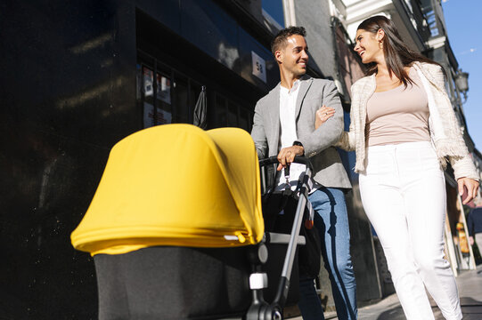 Beautiful Shot Of A Caucasian Couple Pushing A Baby Pram While Walking On The Street