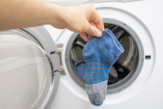 Hand In Front Of Front Loading Washing Machine Found A Blue Missing Sock