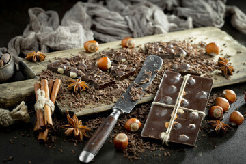 Pieces of dark chocolate and cocoa beans in composition on old background