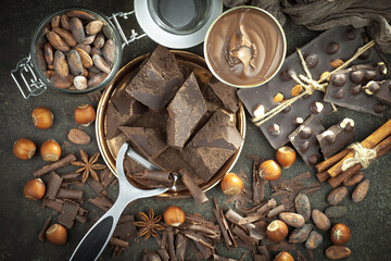 Dark chocolate in a composition with cocoa beans and nuts, on an old background.