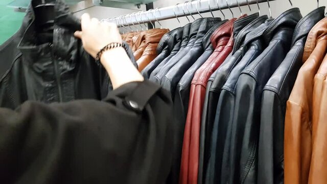 Woman choosing a leather jacket in leather shop