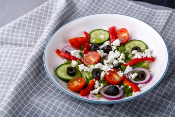 Light plate of Greek salad on a checkered napkin.