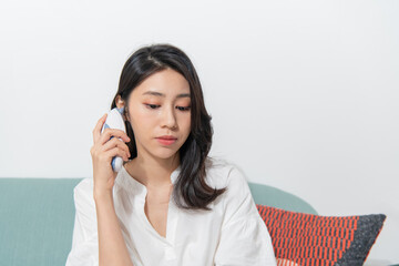 Young Asian woman is measuring her body temperature with ear thermometer