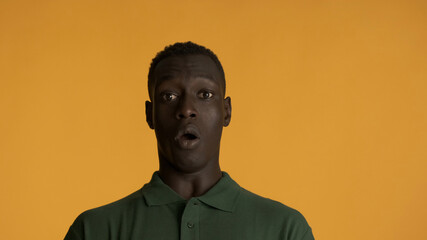 Obraz premium Shocked African American man scaredly looking in camera over yellow background