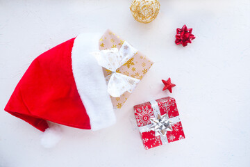 red christmas santa claus hat, gift boxes and christmas tree toys on a white table..