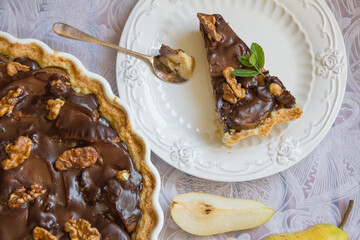 Chocolate pear tart. A portioned slice of chocolate pear tart on a white plate