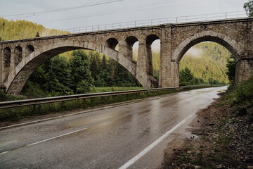 Fototapeta premium Stone railway bridge of the 19th century, old arch bridge over the river, the road passes under the railway bridge