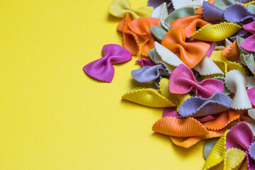 Rainbow color pasta isolated on yellow bristol paper background with copy space  - obrazy, fototapety, plakaty