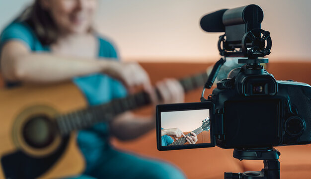 Happy woman teaching guitar lesson on internet with video tutorial - Social distance music concept - Focus on camera