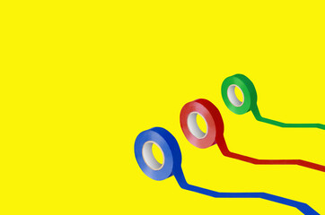 Different color electrical tapes on yellow background