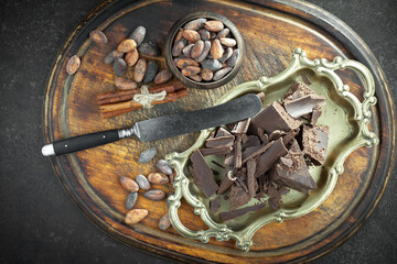 Dark chocolate in a composition with cocoa beans and nuts, on an old background.