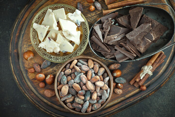 Pieces of dark chocolate and cocoa beans in composition on old background
