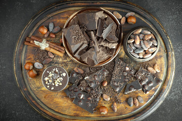 Dark chocolate in a composition with cocoa beans and nuts, on an old background.