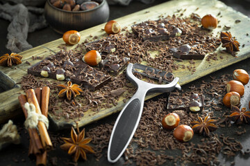 Dark chocolate in a composition with cocoa beans and nuts, on an old background.