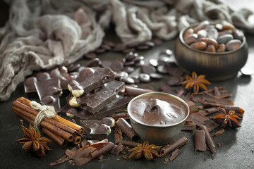 Pieces of dark chocolate and cocoa beans in composition on old background