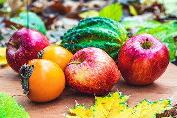 apples, pumpkin and persimmon among fallen autumn leaves