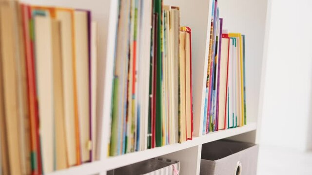 Passing row of books, lying on the bookshelf
