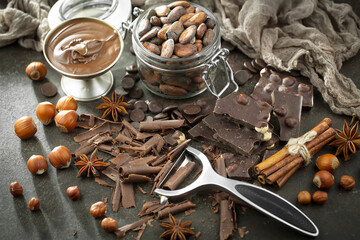 Pieces of dark chocolate and cocoa beans in composition on old background