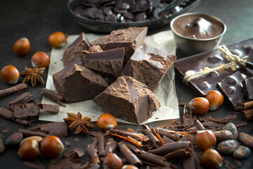 Dark chocolate in a composition with cocoa beans and nuts, on an old background.
