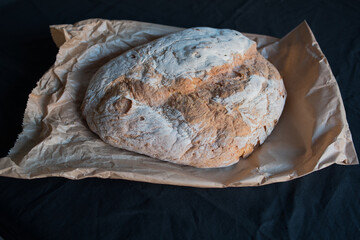 Bread baked in a wood oven. Close up of the piece of bread over the classic caste envelope on a black background.