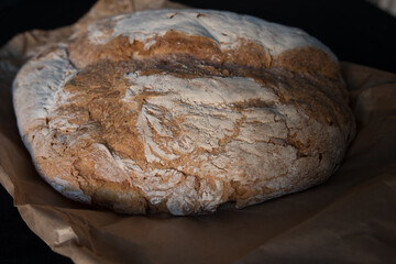 Bread baked in a wood oven. Close up of the piece of bread over the classic caste envelope on a black background.
