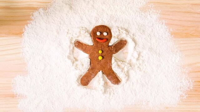 Stop motion animation of a gingerbread man making snow angel on flour.