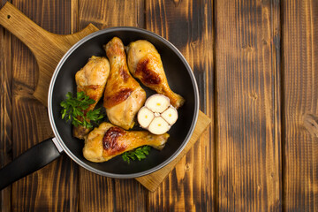 Top view of fried chicken legs in the frying pan on the wooden background with copy space