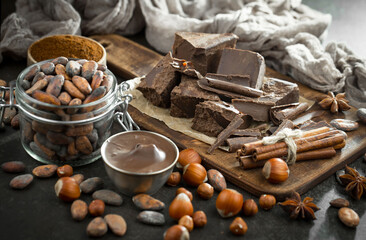 Dark chocolate in a composition with cocoa beans and nuts, on an old background.