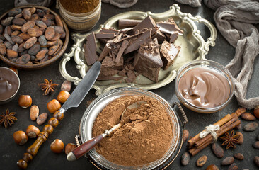 Pieces of dark chocolate and cocoa beans in composition on old background