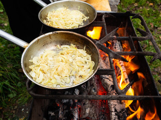 pans on the fire on the grill. roasting onions in the bright flames of the brazier.