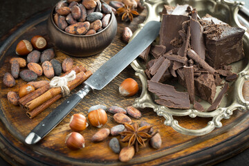 Dark chocolate in a composition with cocoa beans and nuts, on an old background.