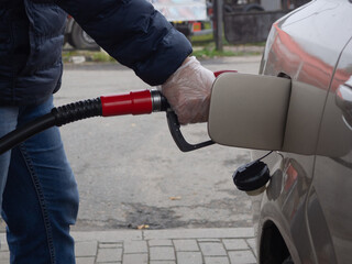 Obraz premium a man fills a car with gasoline in a disposable glove. safety from germs. stop the coronavirus