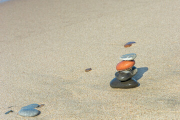 Fototapeta na wymiar Pyramid of stones on the sand. Harmony and meditation concept. Copy space, selective focus