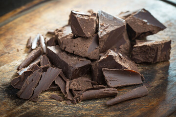 Pieces of dark chocolate and cocoa beans in composition on old background