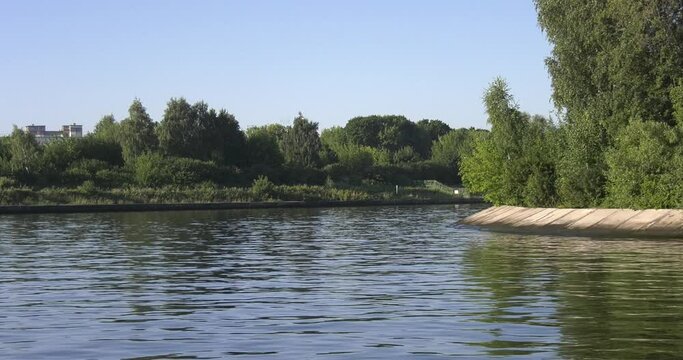 4K high quality calm windless bright summer morning video of Moscow Channel yacht club embankment, green trees, wooden pier and shore with moored anchored boats and yachts near Moscow, Russia