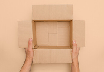 male hands presents a brown open carton package without content in top view from above