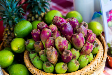 Pineapples, limes and a basket of edible cactus Opuntia ficus-indica fruits
