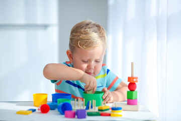 Little boy 2 years old is played with a colors toys. Educational logic toys for children. Montessori games for child development.