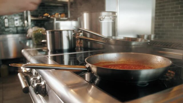Chef cooking tasty pasta tomato sause on restaurant kitchen add spices, traditional italian food, high kitchen cafe, man preparing dinner
