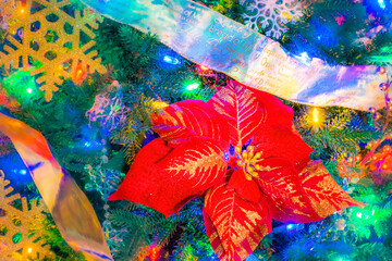 Ribbon garlands, snowflakes and a large red Poinsettia decorate a Christmas tree.