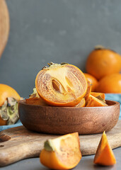 Juicy cut persimmon in a wooden cup with copies of space.