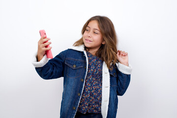 Little caucasian girl with beautiful blue eyes wearing denim jacket standing over isolated white...