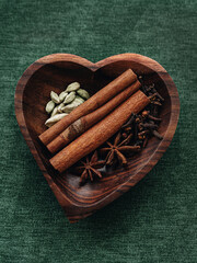 Spices for mulled wine: cinnamon sticks, star anise, cardamom are on a heart-shaped wooden plate. Christmas spices. Spices for food and drinks. Spices for the grok. Train herbs.