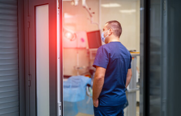 Horizontal portrait of a medic from the back. Doctor in mask standing at surgery room.