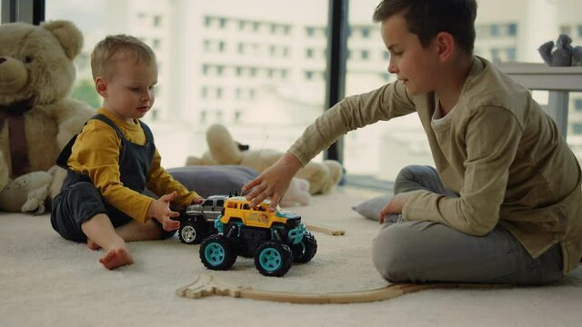 Nice kids sharing toy cars on carpet. Amazing kids playing together indoors.