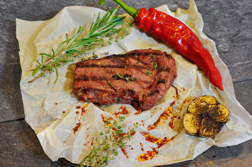 Sliced grilled beef barbecue Striploin steak with chimichurri sauce on cutting board on dark wooden background